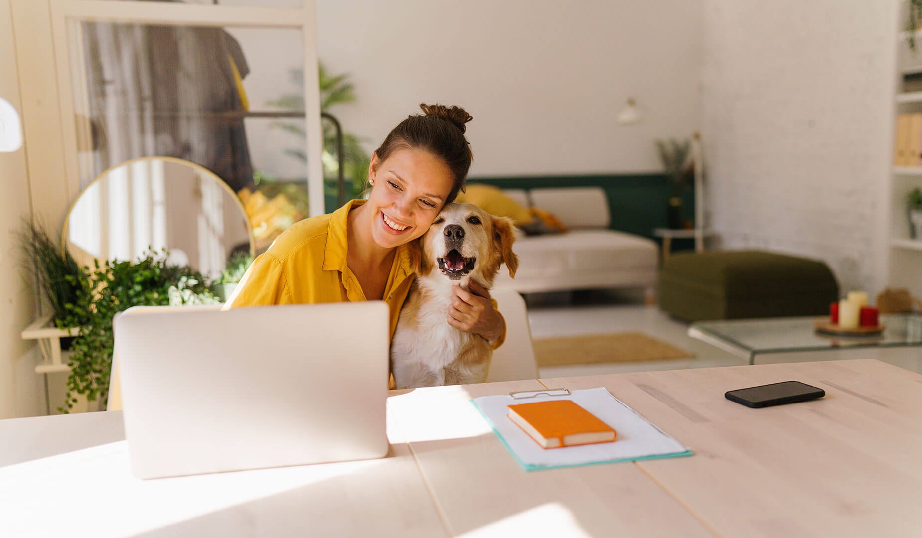 woman with dog sitting at dining table with laptop