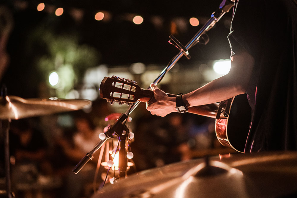 man facing crowd holding guitar and singing in outdoor venue in austin, tx