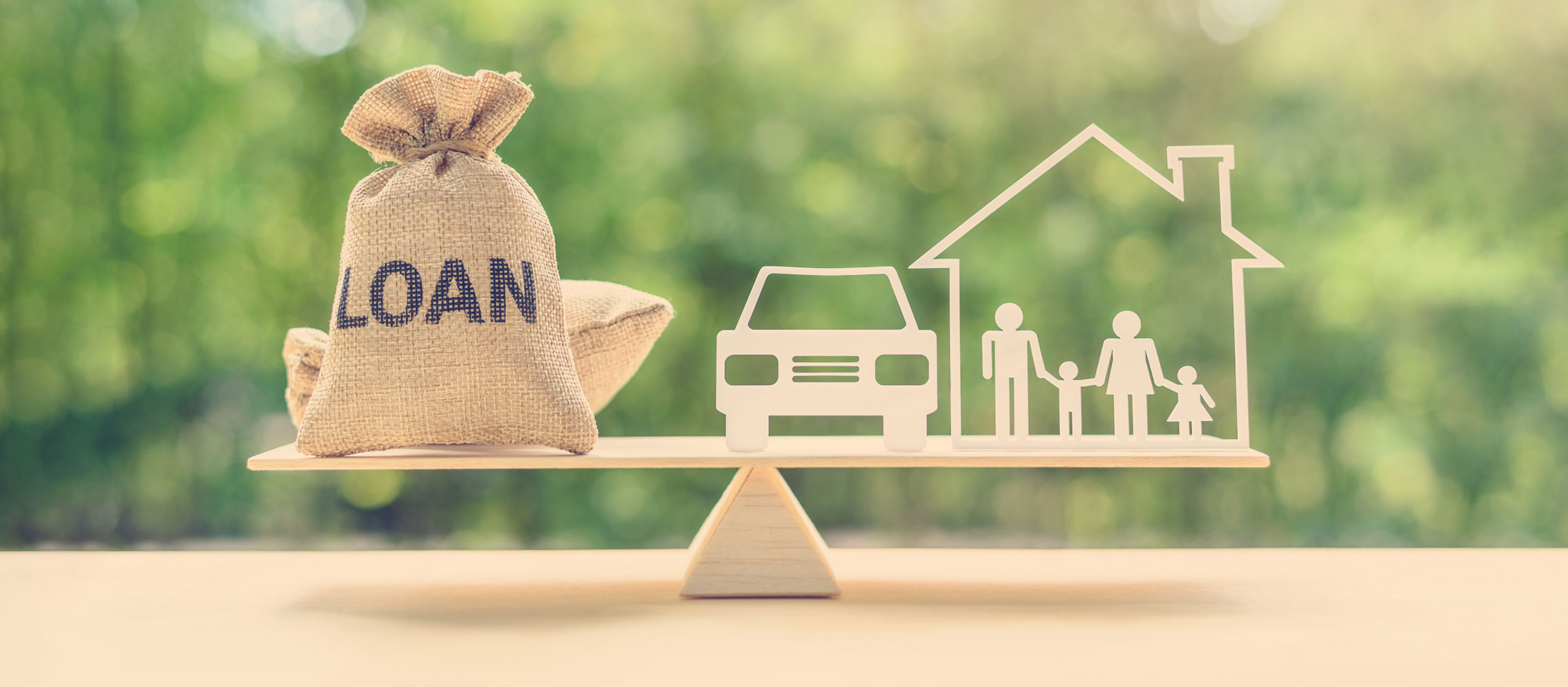 bag titled loan on scale with car and house wooden cutouts
