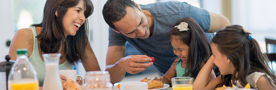 parents feeding their two daughters fruit