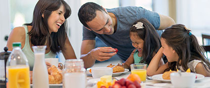 parents feeding their two daughters fruit