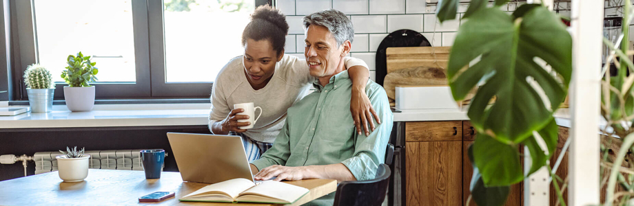 couple sitting at dining table looking at a laptop