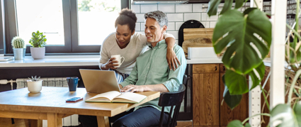 couple sitting at dining table looking at a laptop