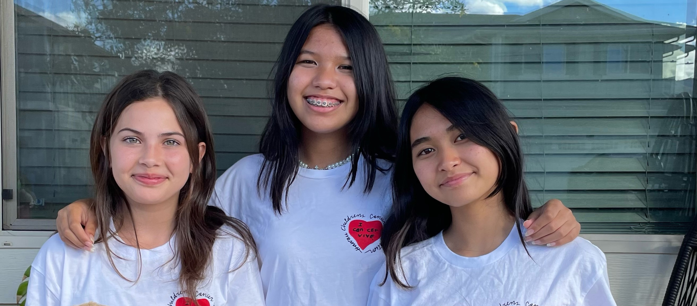 3 Girls wearing Hawaii Children's Cancer Foundation shirts