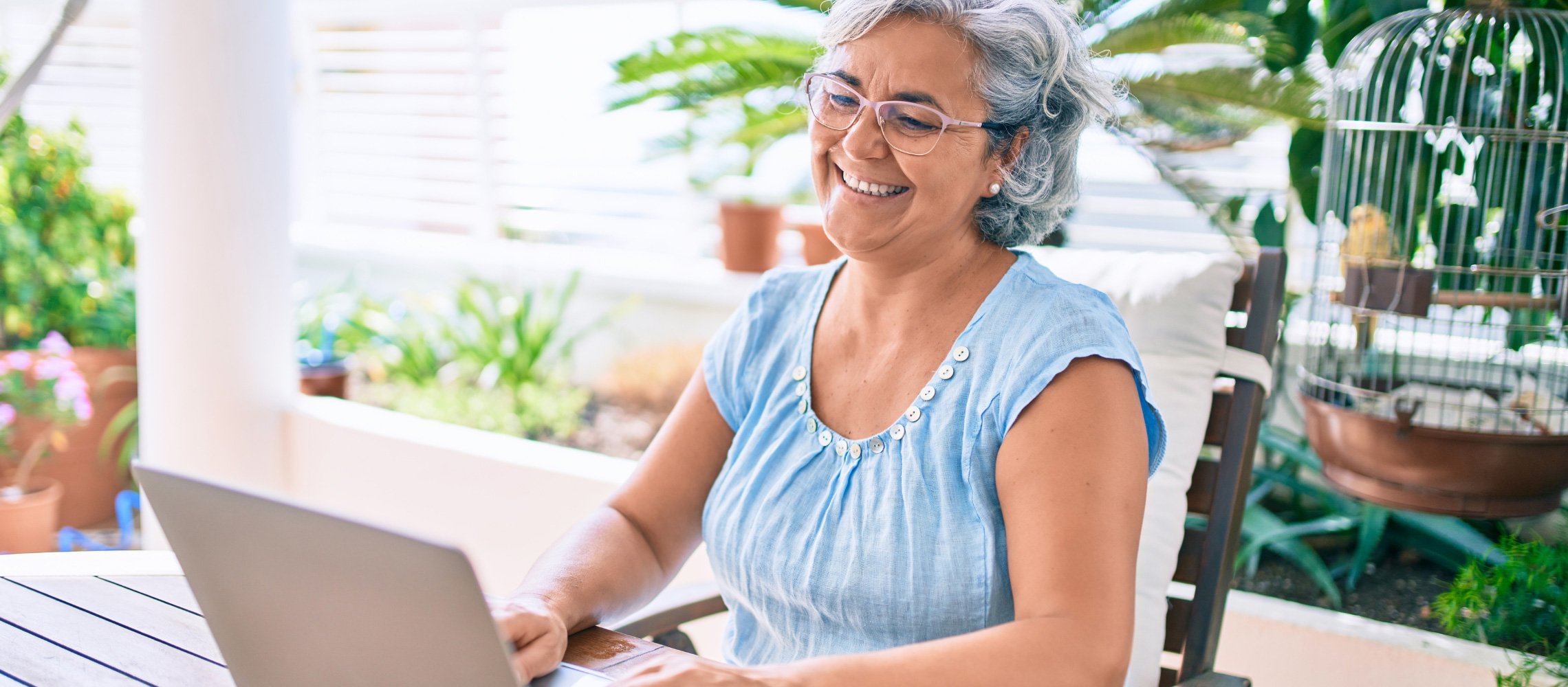 Elderly lady smiling at laptop while seated