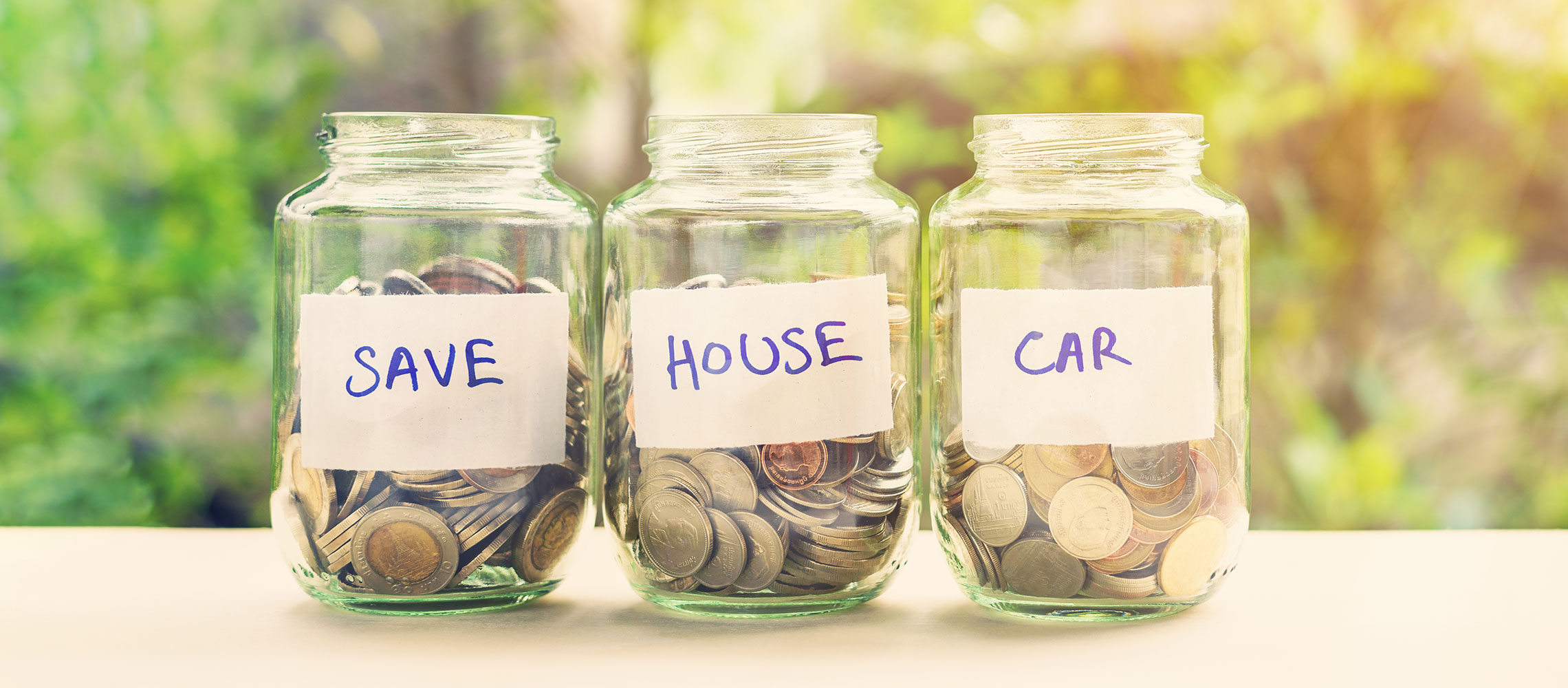 jars with coins and words 'save' 'house' and 'car' written on them