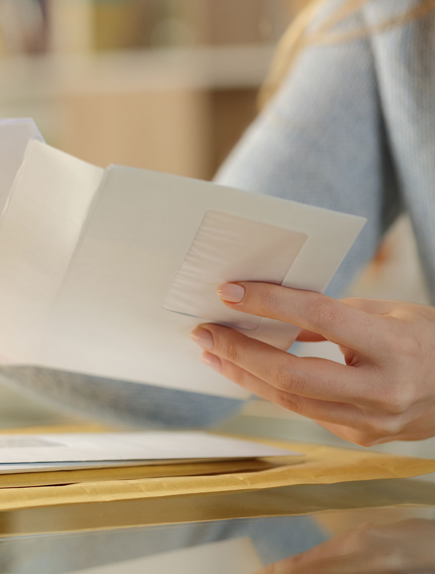 close up of a woman opening mail, watch out for fake check scams