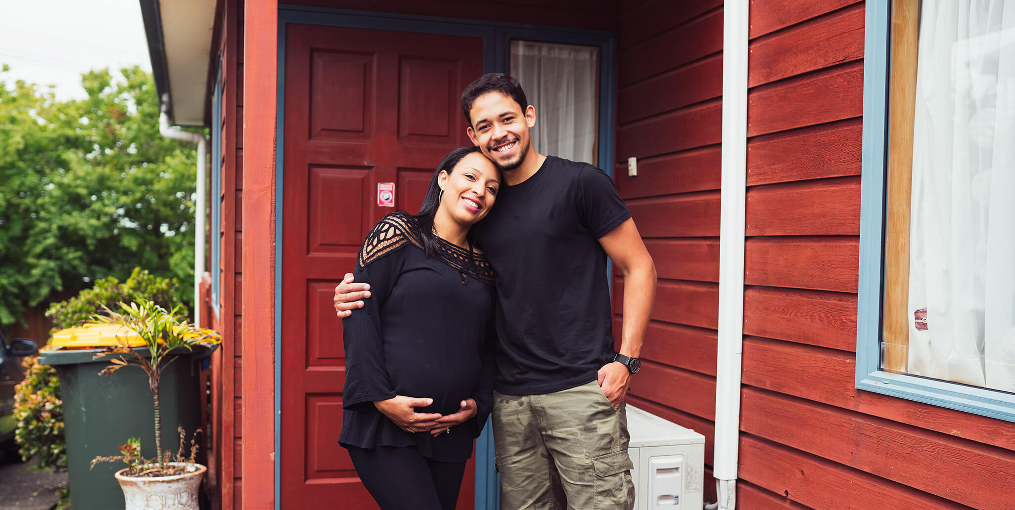 couple standing in front of a red house