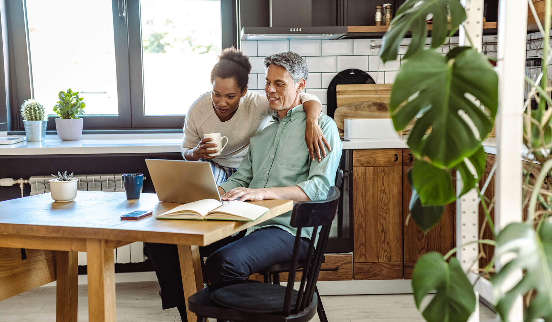 couple sitting at dining table looking at a laptop