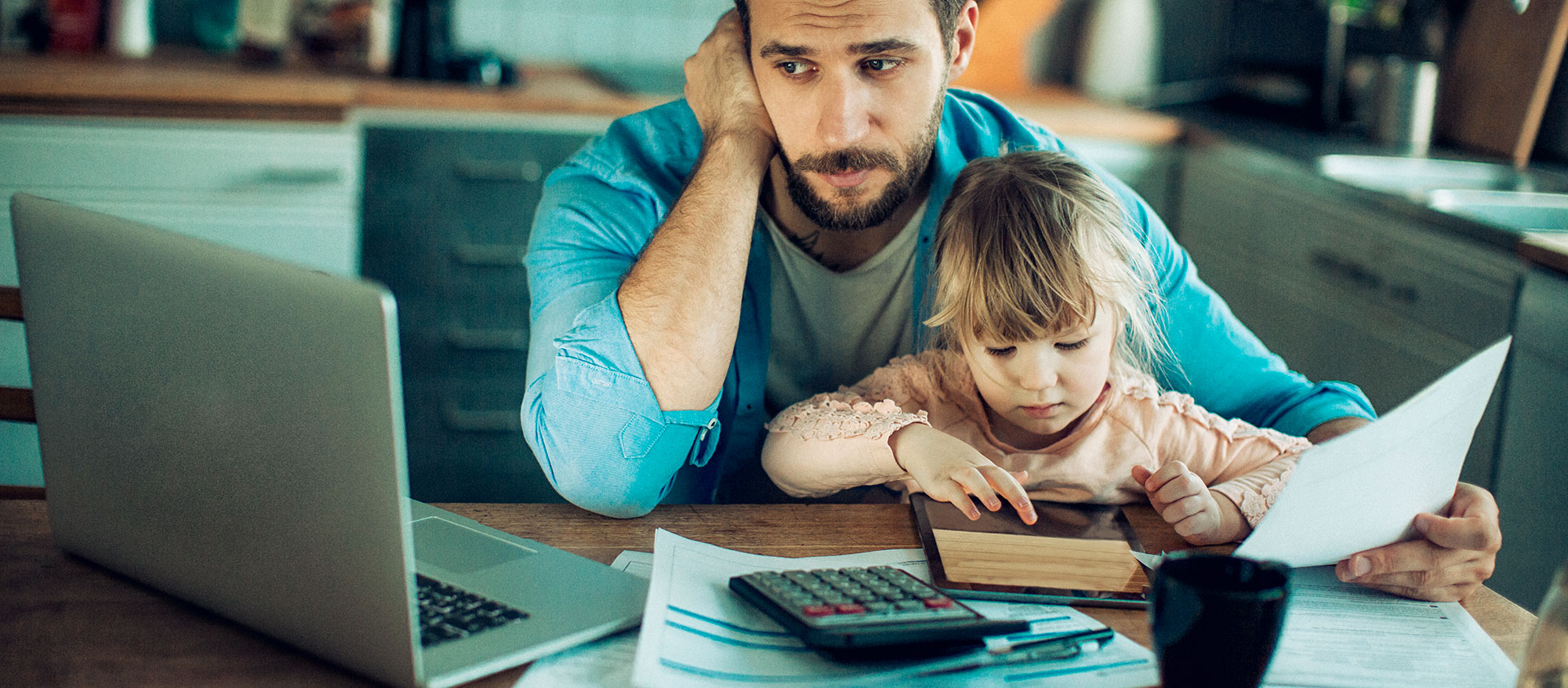 father using his laptop with his daughter beside him