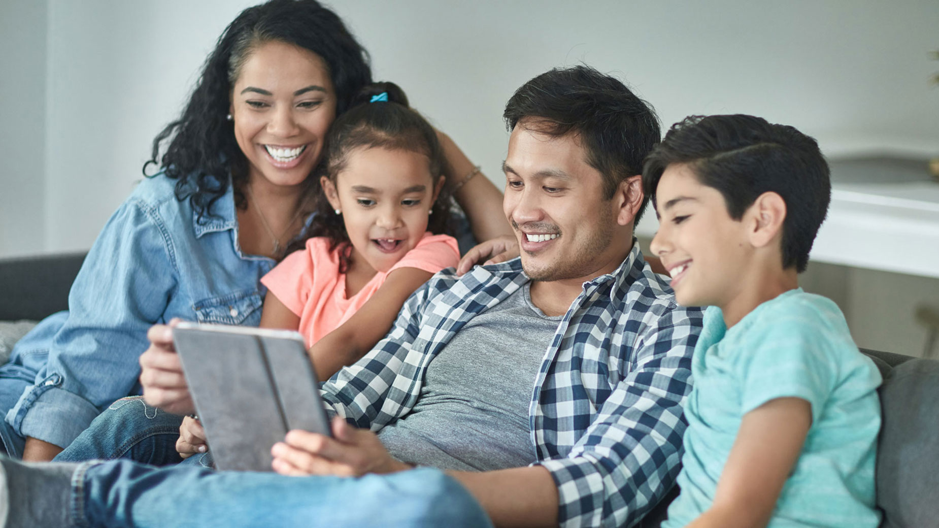 family sitting on a couch looking at a tablet
