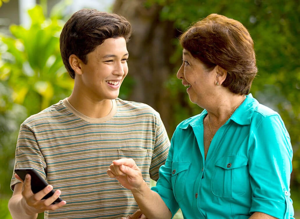 grandson teaching grandma how to use her smartphone