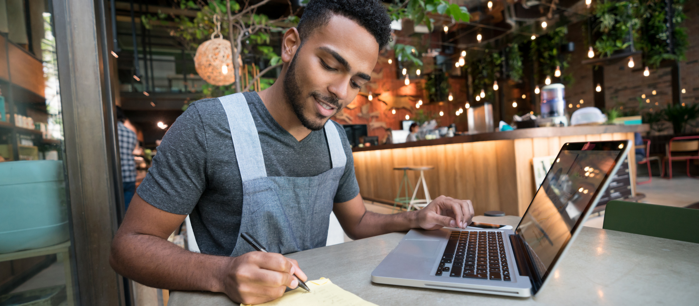 Man taking notes and using laptop computer