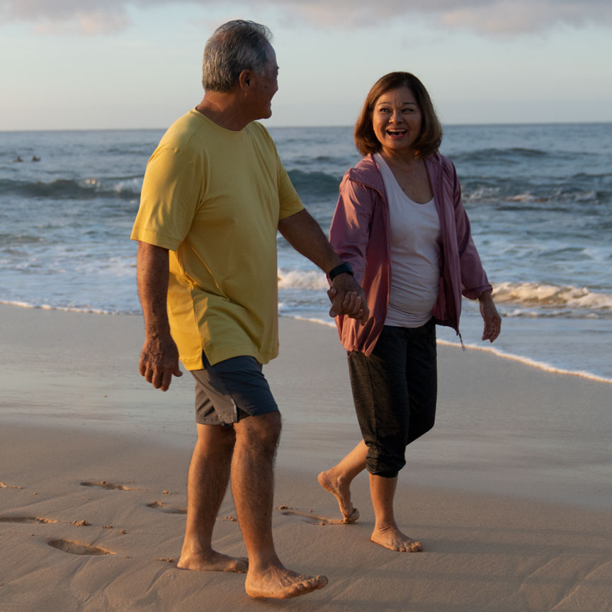 elderly couple walking on a beach