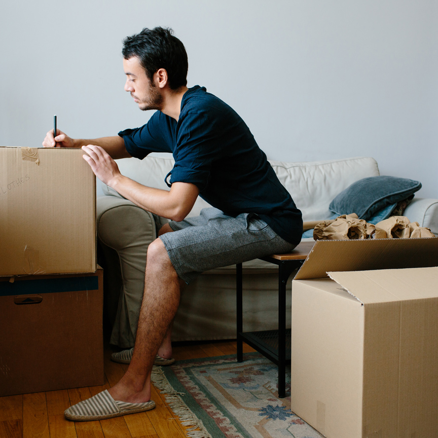 man writing on cardboard box