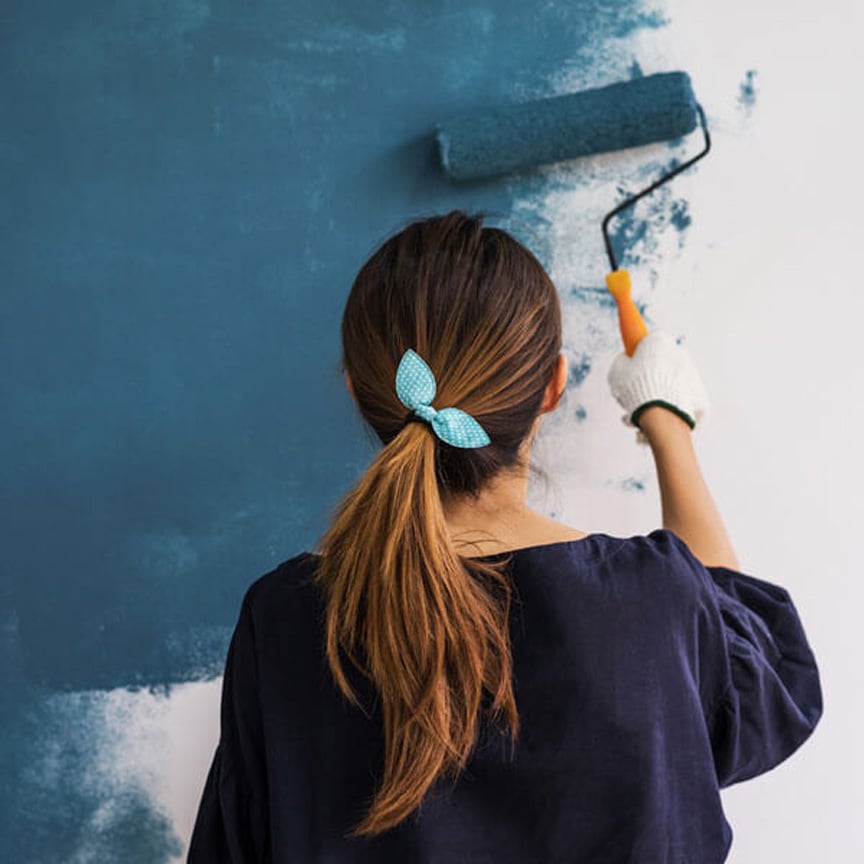 woman painting teal wall