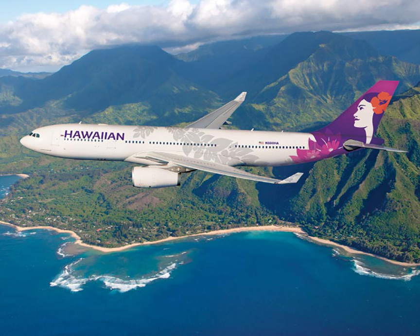 An airplane flying high above the ocean with a Hawaiian island in the background.