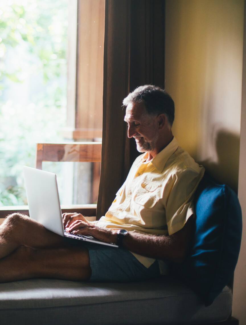 man sitting by window with laptop