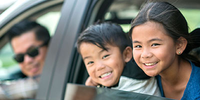 father and kids smiling in car